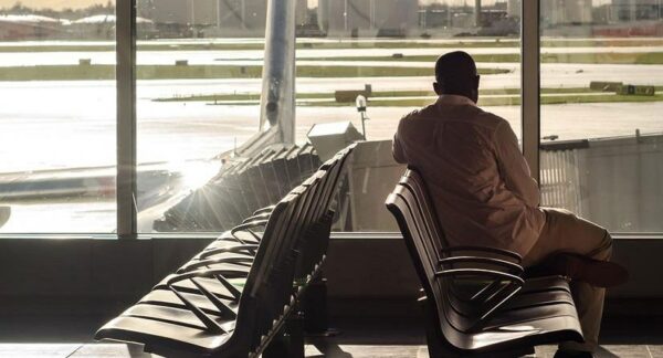 Flight Delays and Cancellations advice from Total Travel Protection. Traveller waiting in airport.