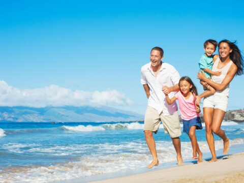 Cancer travel insurance - family running on beach